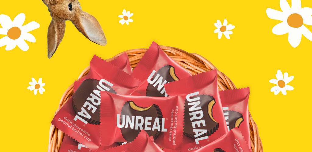 Basket of UNREAL dark chocolate peanut butter cup candies on yellow background with daisies and a rabbit ear