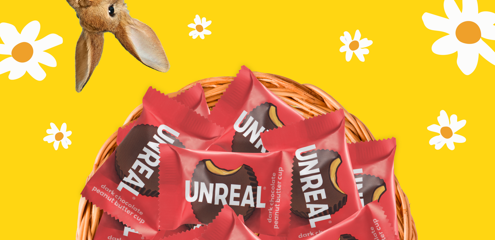 Basket of UNREAL dark chocolate peanut butter cup candies on yellow background with daisies and a rabbit ear