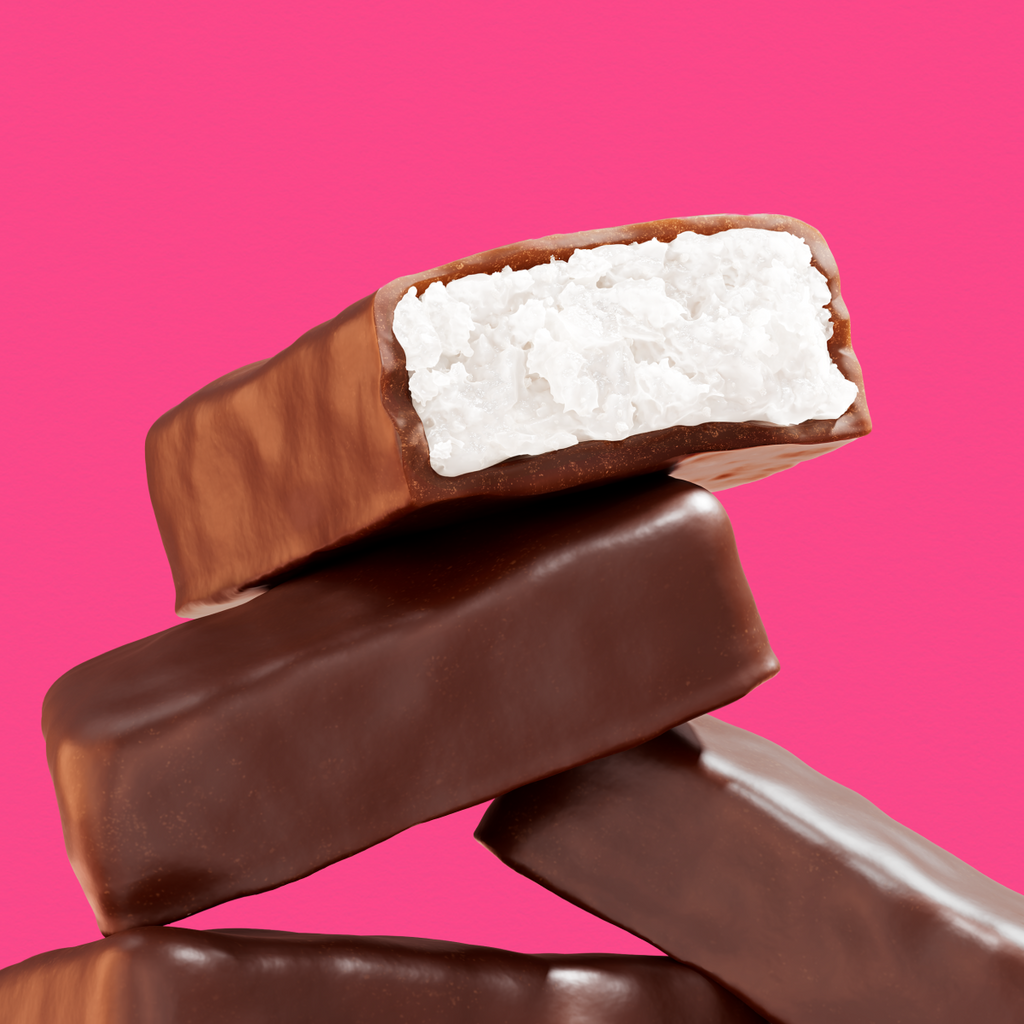 Stacked chocolate-covered coconut bars with one cut open revealing white shredded coconut filling on bright pink background