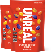 Front of two Peanut Butter Drops bags with UNREAL logo, candy pieces, and 33 percent less sugar claim